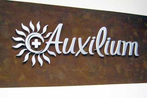 Scritta effetto metallo silver installata sulla parete della reception Auxilium